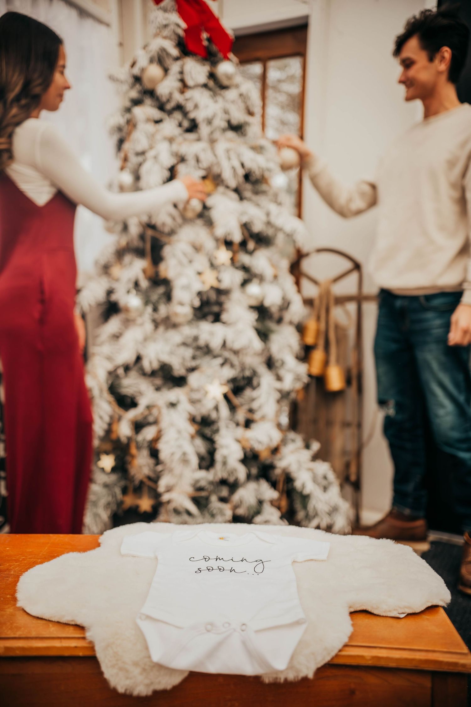 A festive white flocked Christmas tree stands in the corner near a wooden table with decorative elements.