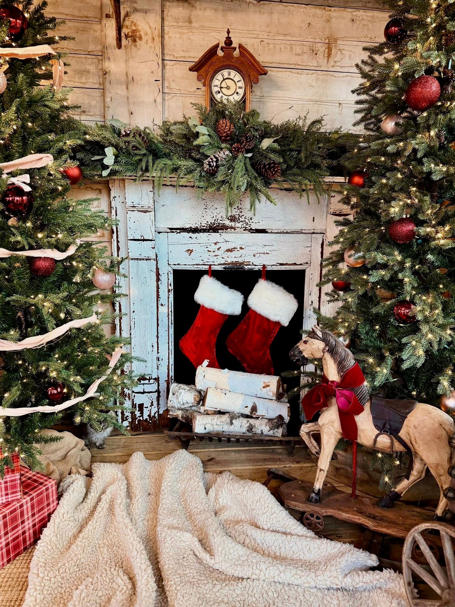 A cozy Christmas scene with rustic white shutters, red stockings, and a decorated tree against a weathered wood wall.