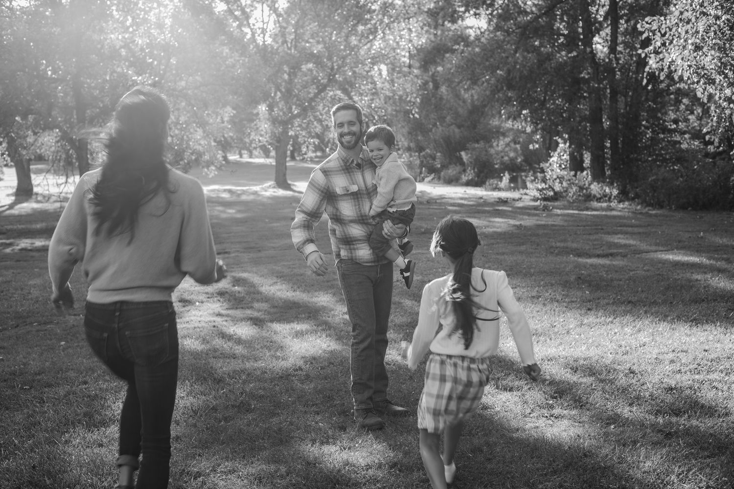 A group walks together along a sunlit path through a park on a bright afternoon.