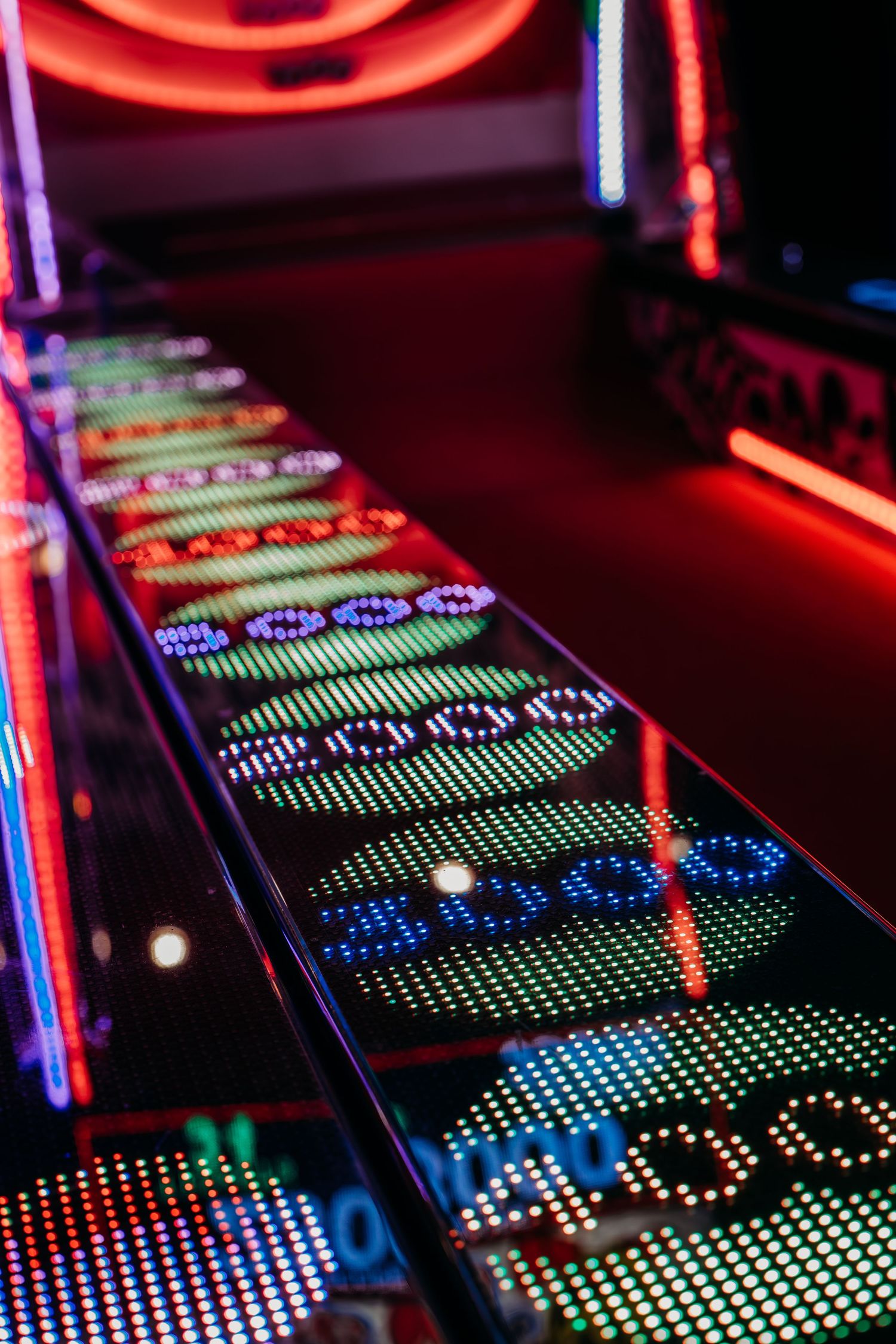Colorful LED display panels showing digital patterns in red, blue and green lights at an arcade or gaming venue.