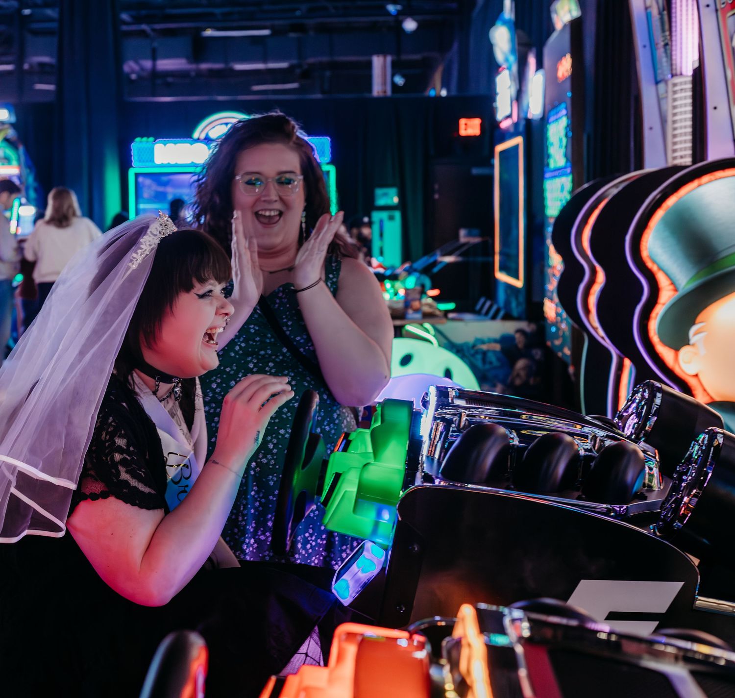 Performers on stage at a nightclub with colorful neon lighting and DJ equipment in the background.