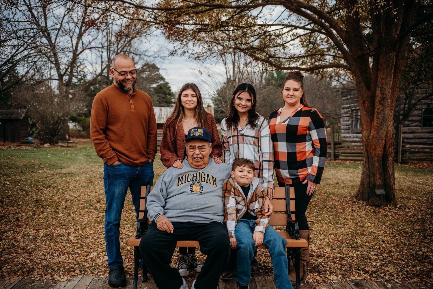A group enjoying a fall photo session together in a rustic outdoor setting with autumn leaves on the ground.