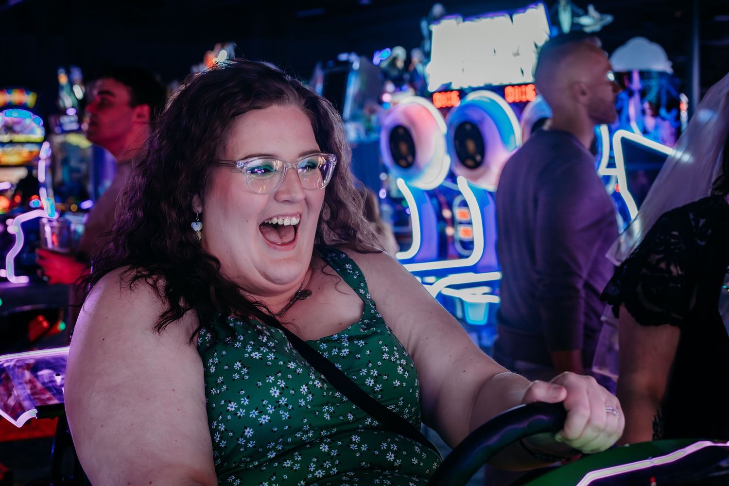 A lively crowd enjoys a night out at a bar with colorful neon lighting in the background.