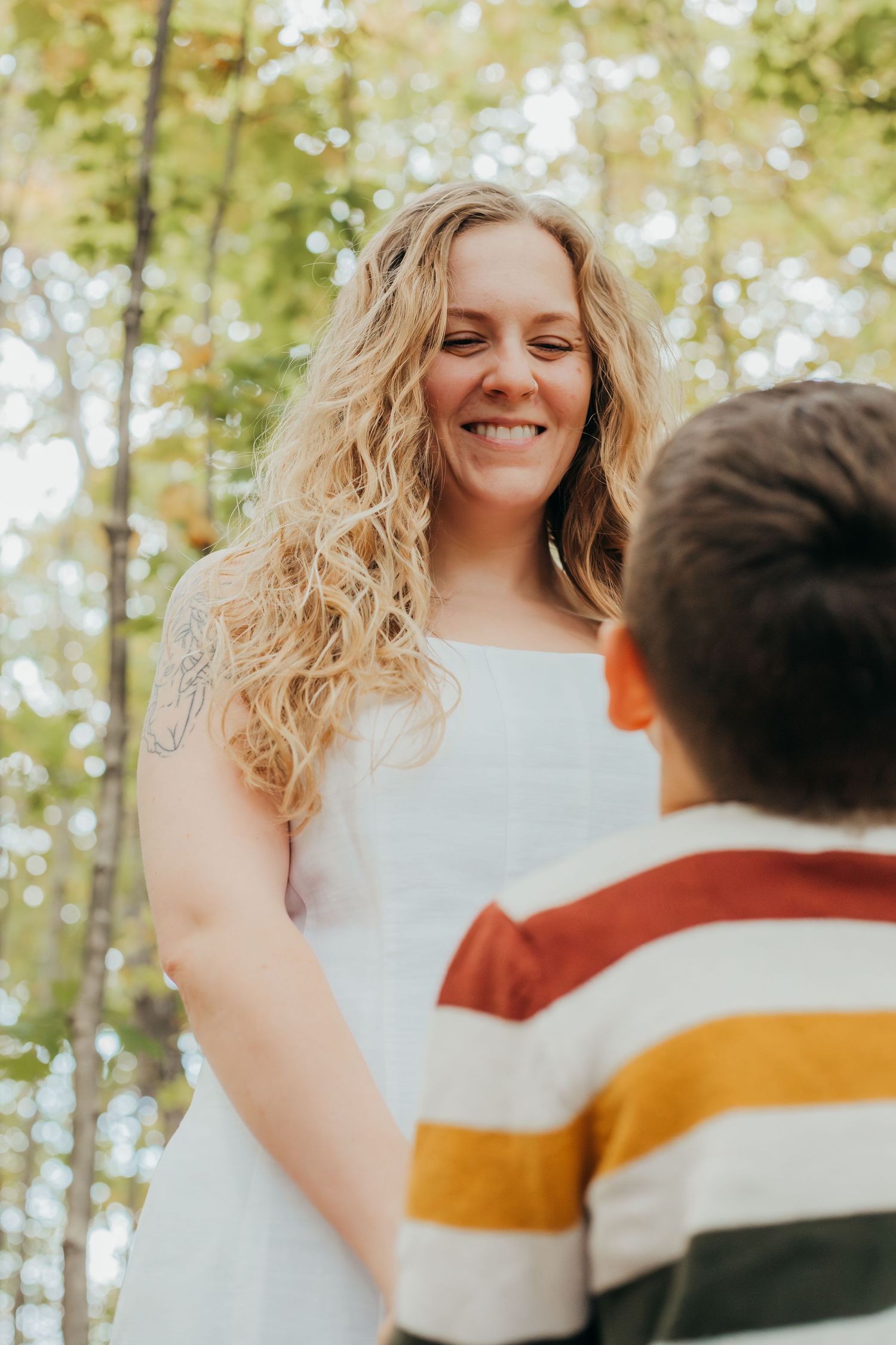A joyful wedding moment captured in a bright forest setting with natural sunlight filtering through the trees.
