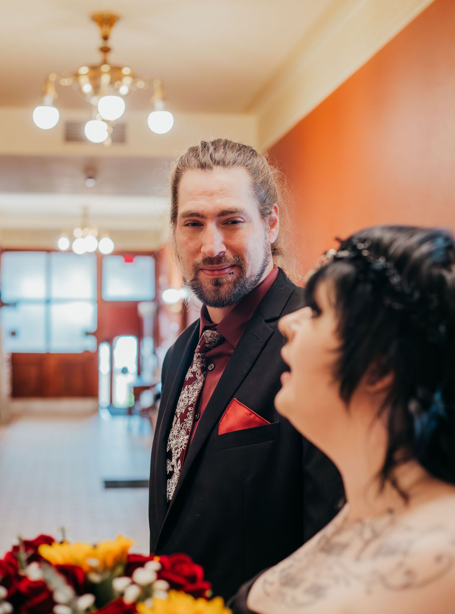A wedding celebration sequence showing candid moments between a couple in formal attire with orange walls and chandeliers.