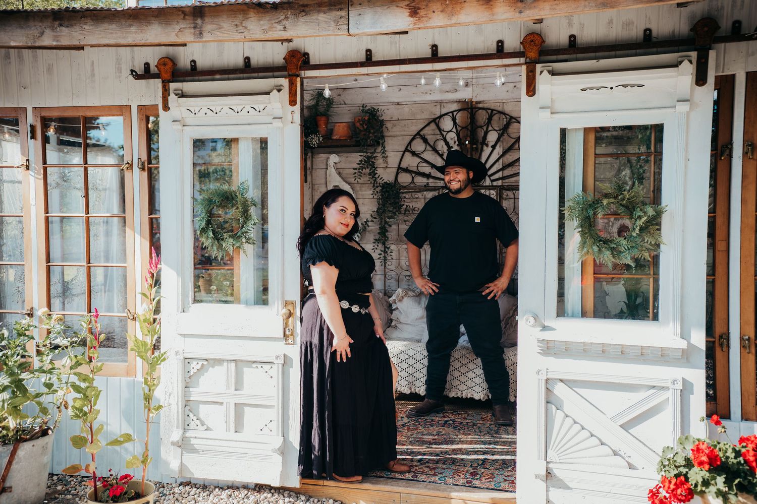 A rustic brick venue entrance decorated with white trim and colorful potted flowers creates a welcoming atmosphere.