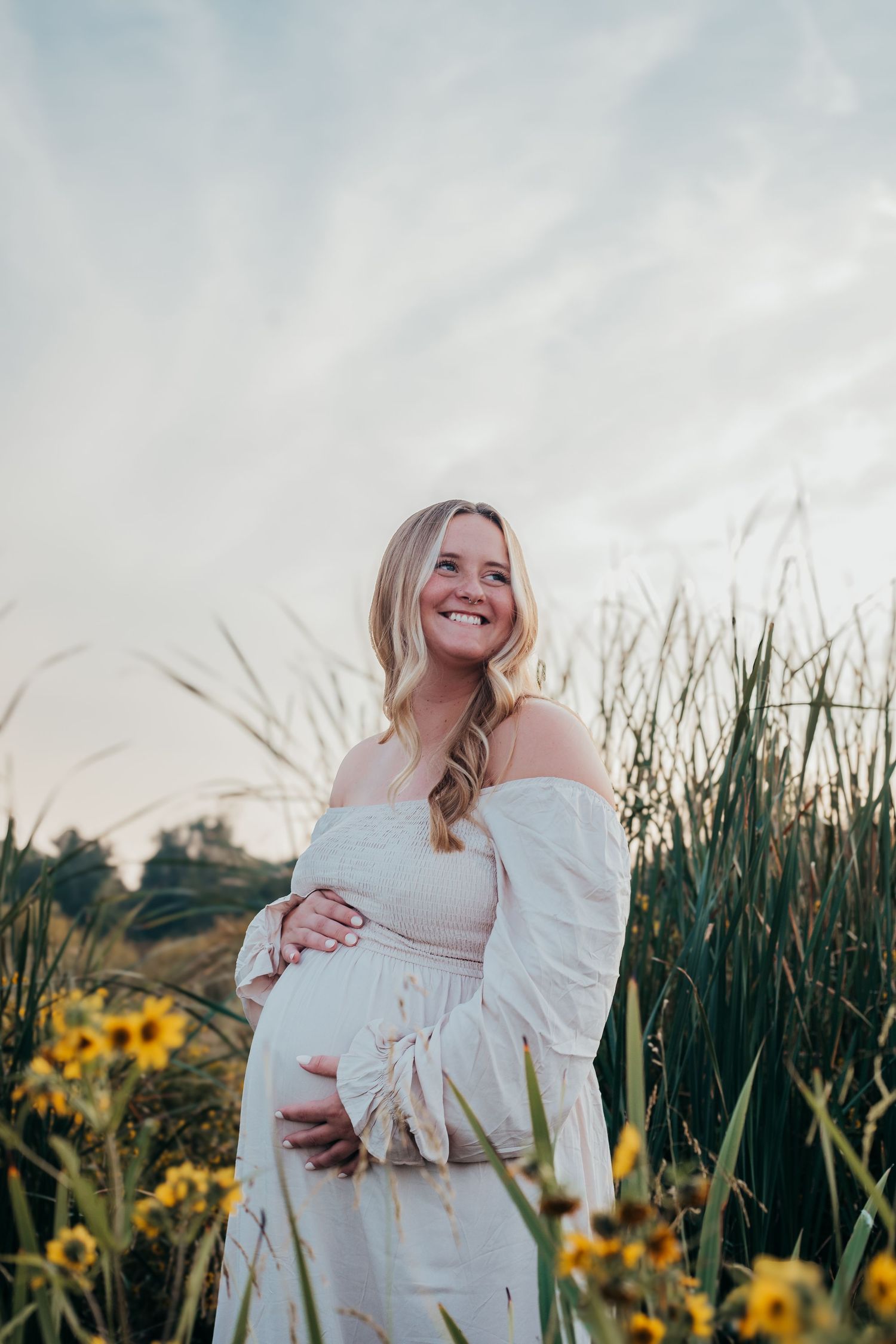 A series of maternity photos showing a woman in white dress posing in a field with tall grass and sunflowers at sunset.