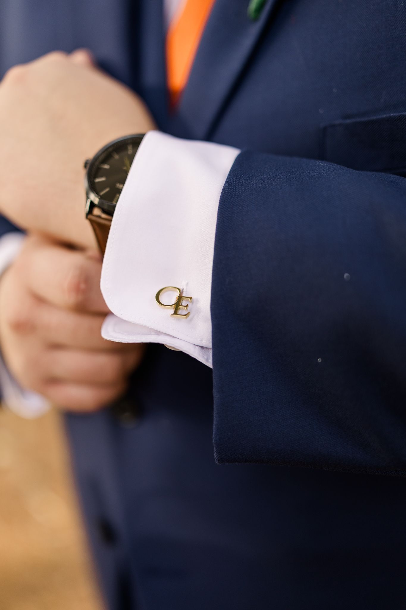 Close-up of groom adjusting cufflinks before wedding ceremony, capturing elegant wedding day details.