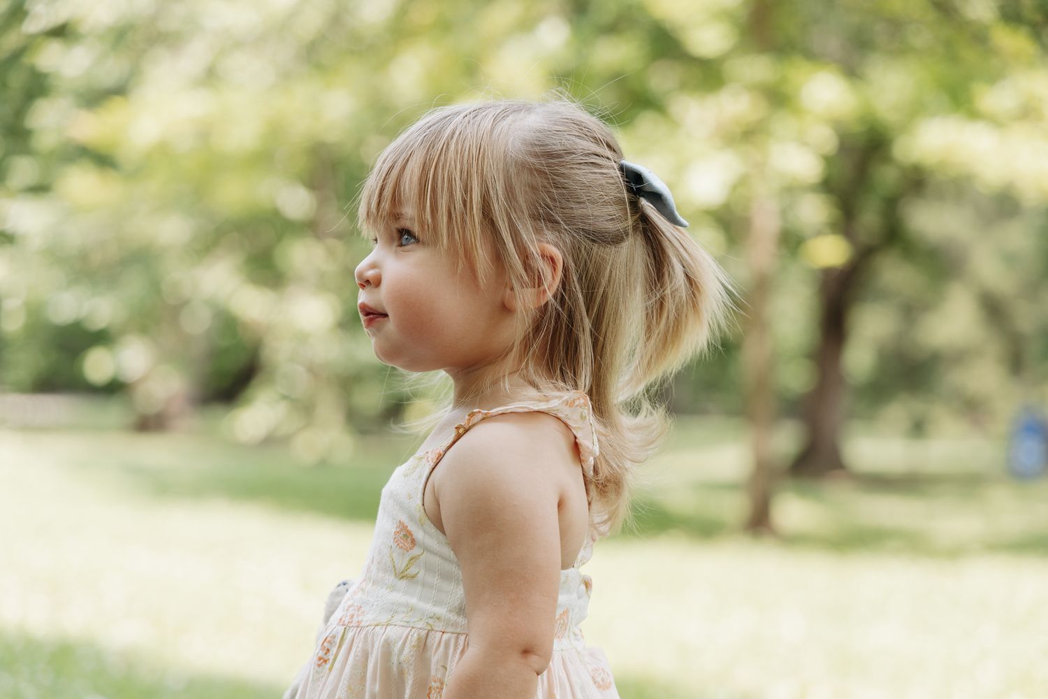 light and airy photo of a young girl side profile standing in a field.