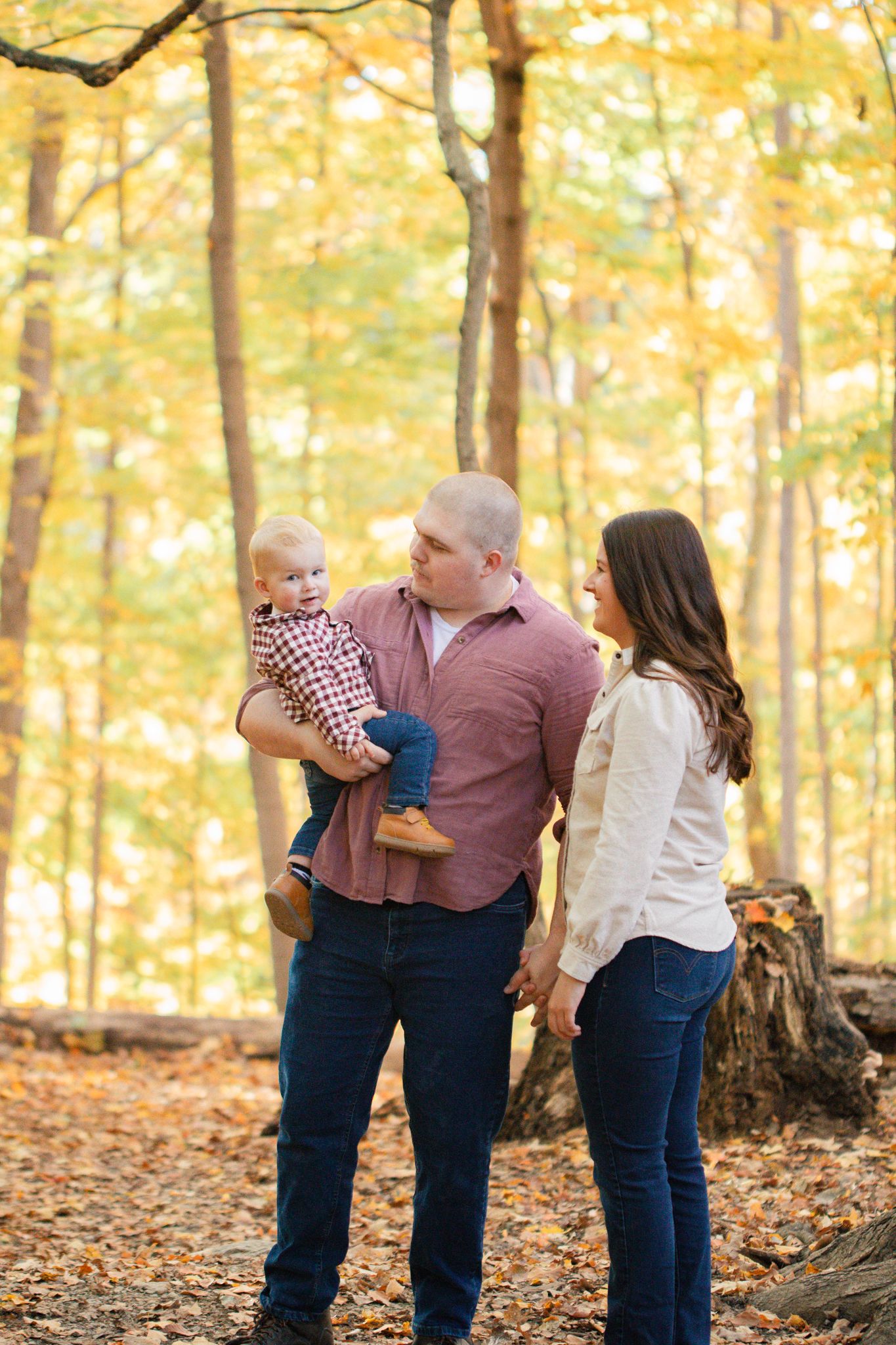 light and airy photo of a family standing in the woods with their young son