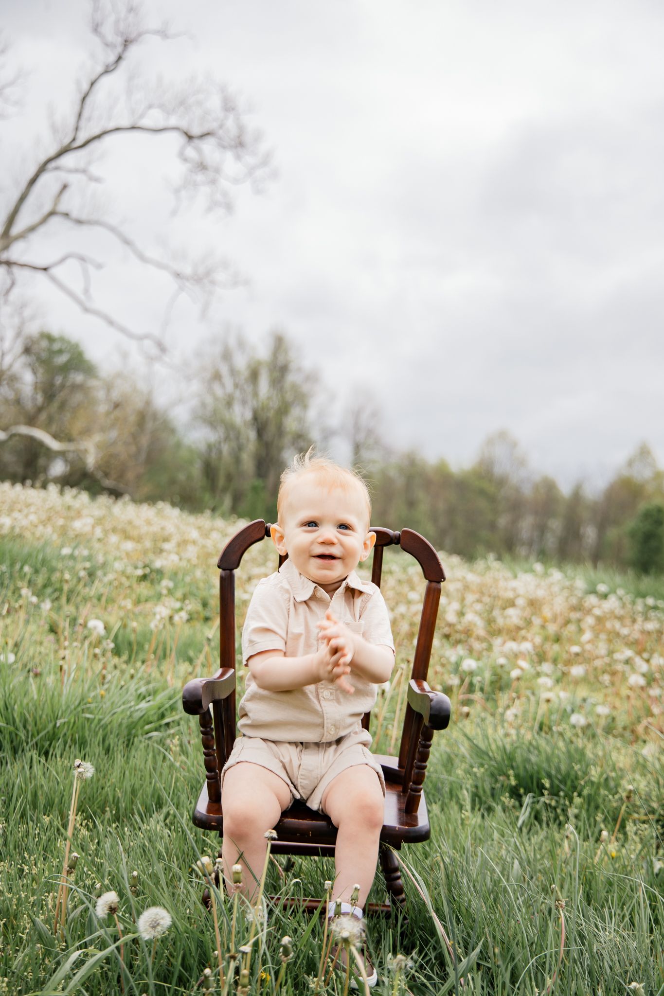 light and airy photo of a young boy sitting in a chair laughing.