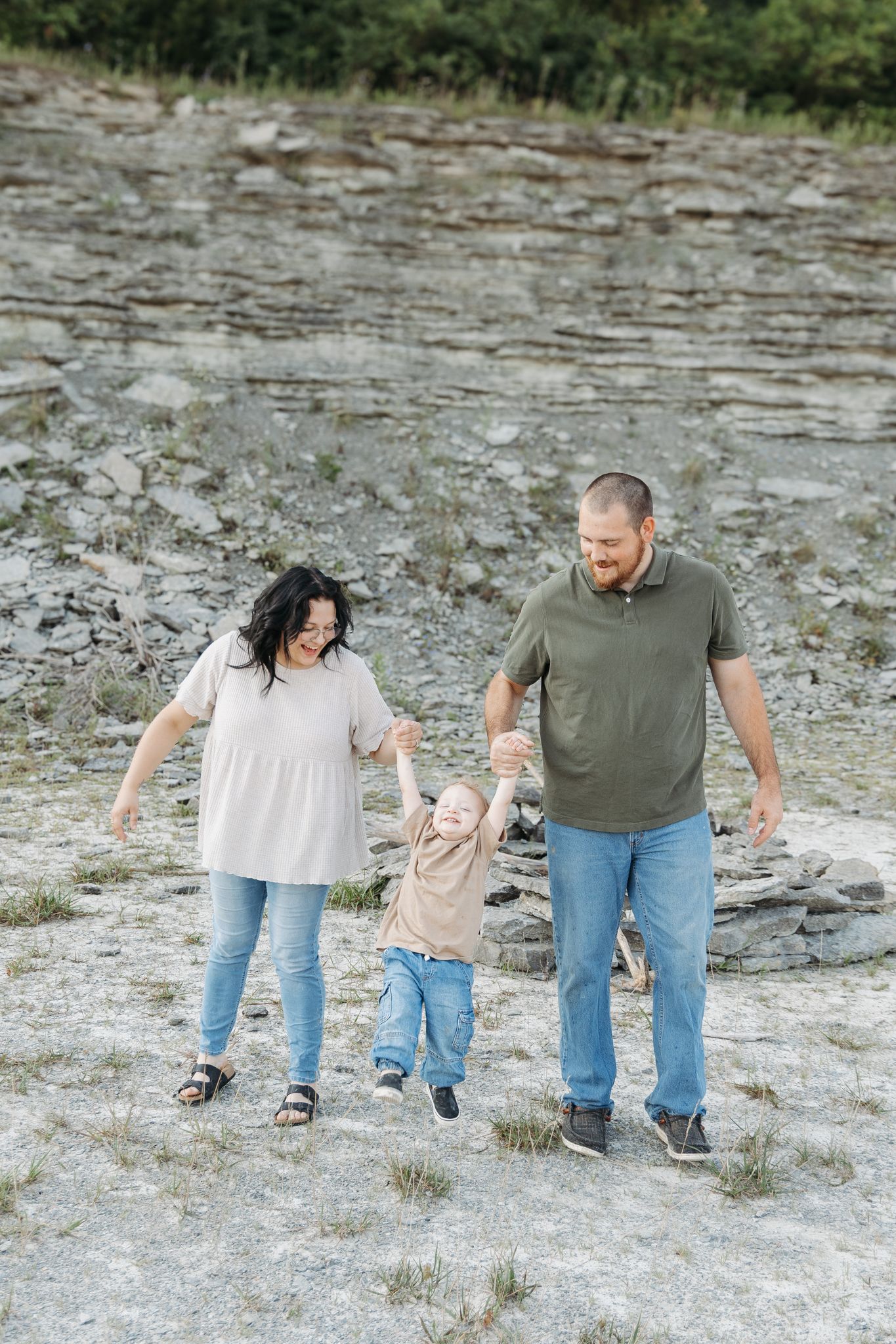 light and airy family photo of parents swinging their young son