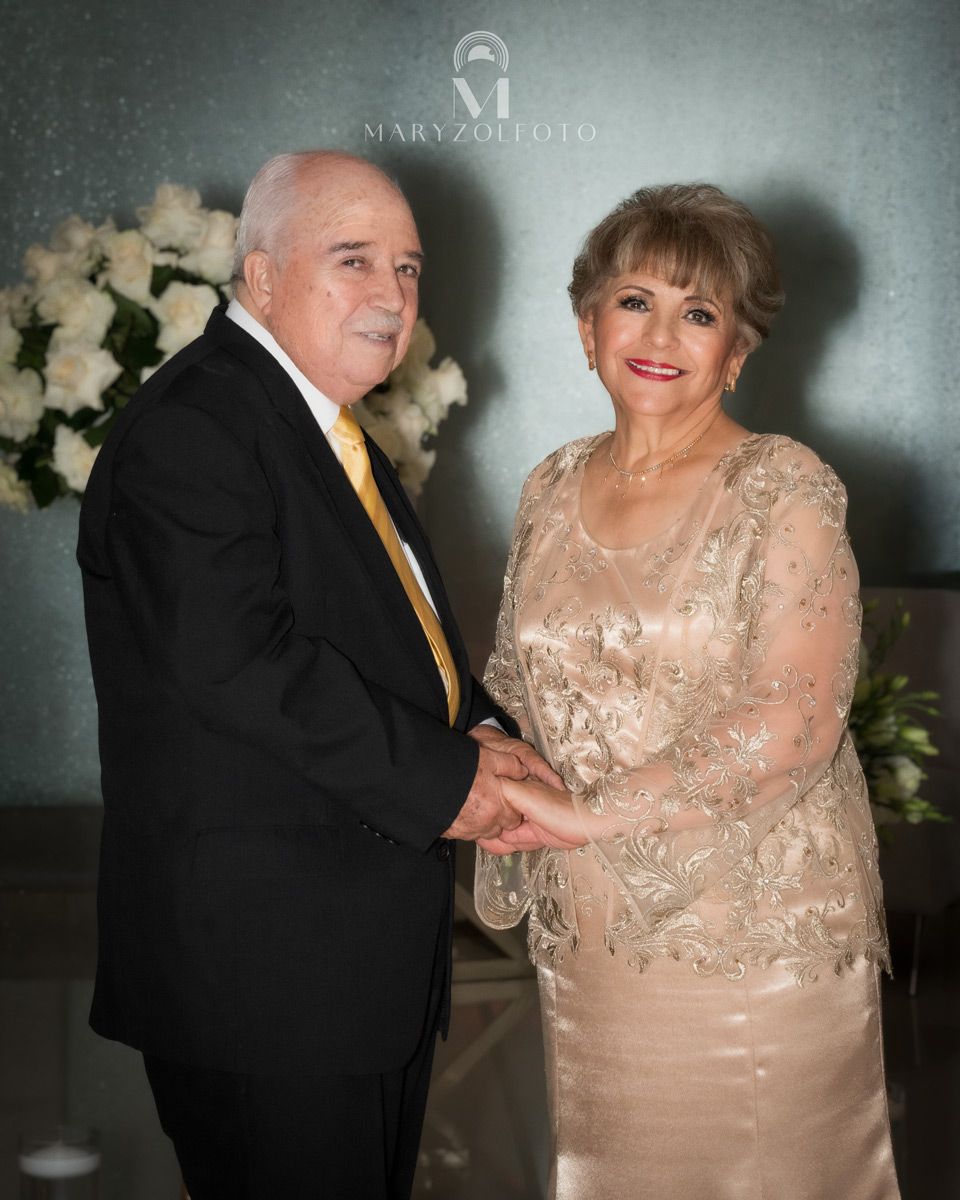 Pareja de adultos mayores felices de pie vestidos formalmente, se están tomando de las manos.