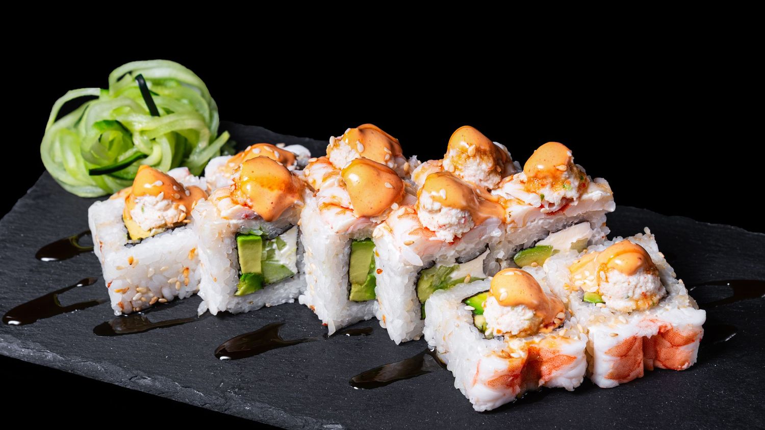 Rollo de sushi con camarón y ajonjolí por fuera, relleno de aguacate, queso crema y pepino, decorado con mayonesa picante y salsa Tampico.