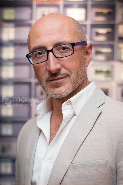 Retrato de hombre profesionista sonriendo, usando saco beige con camisa blanca.