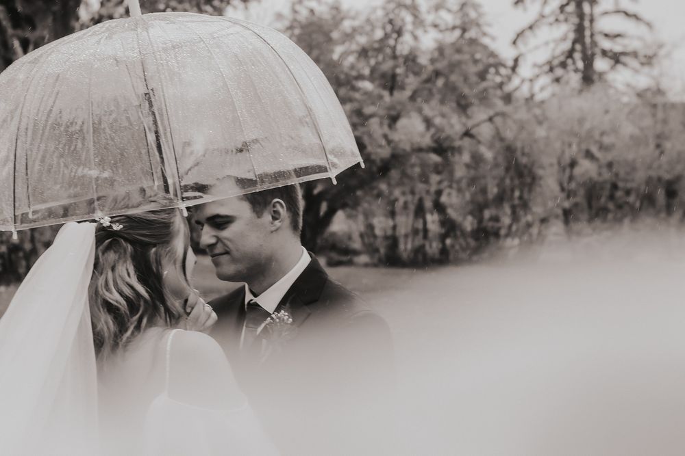 Calgary, Alberta Wedding bride and groom in rain with clear umbrellas
