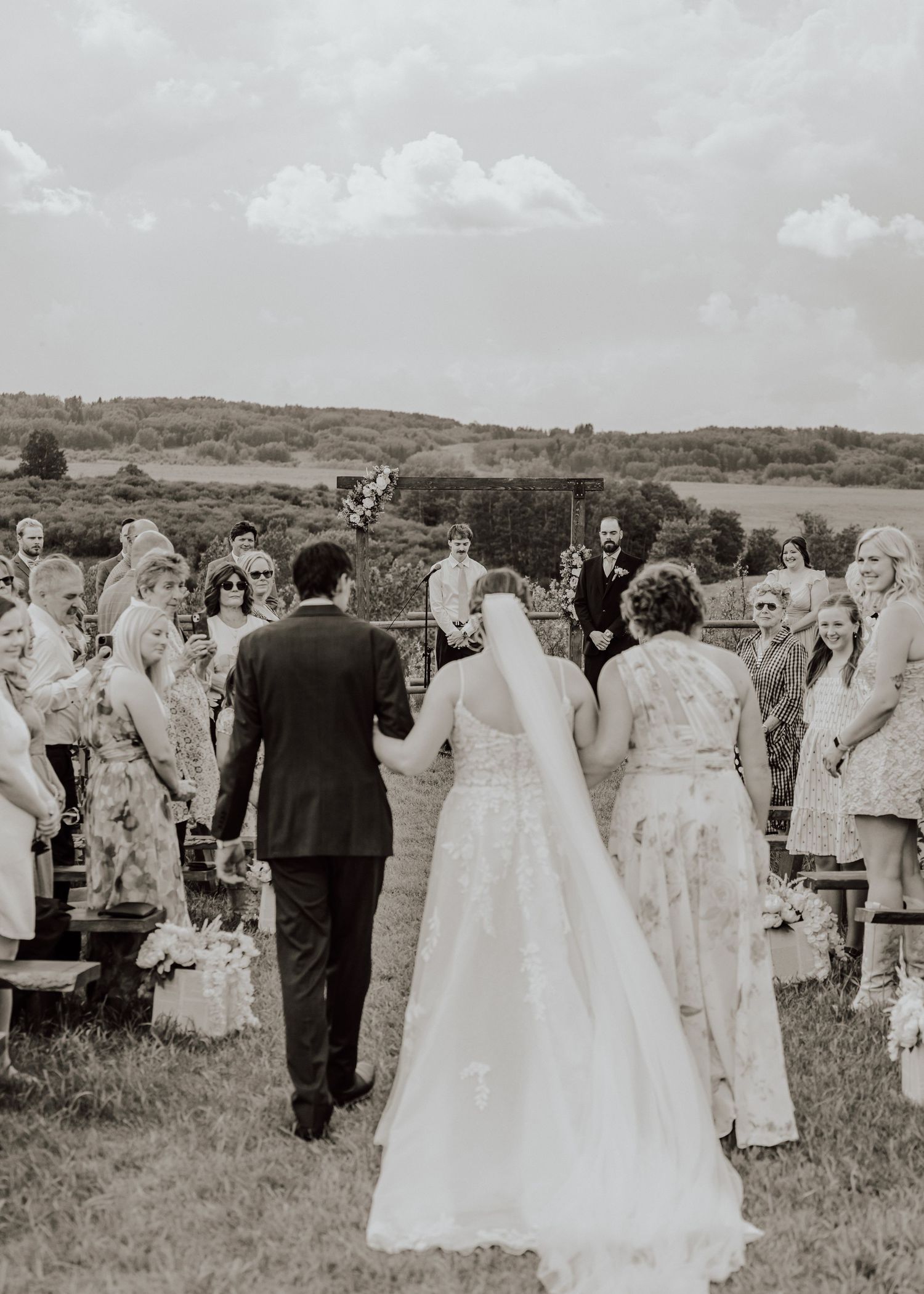 A vintage black and white photograph shows a large gathering of people in formal attire on a grassy field.