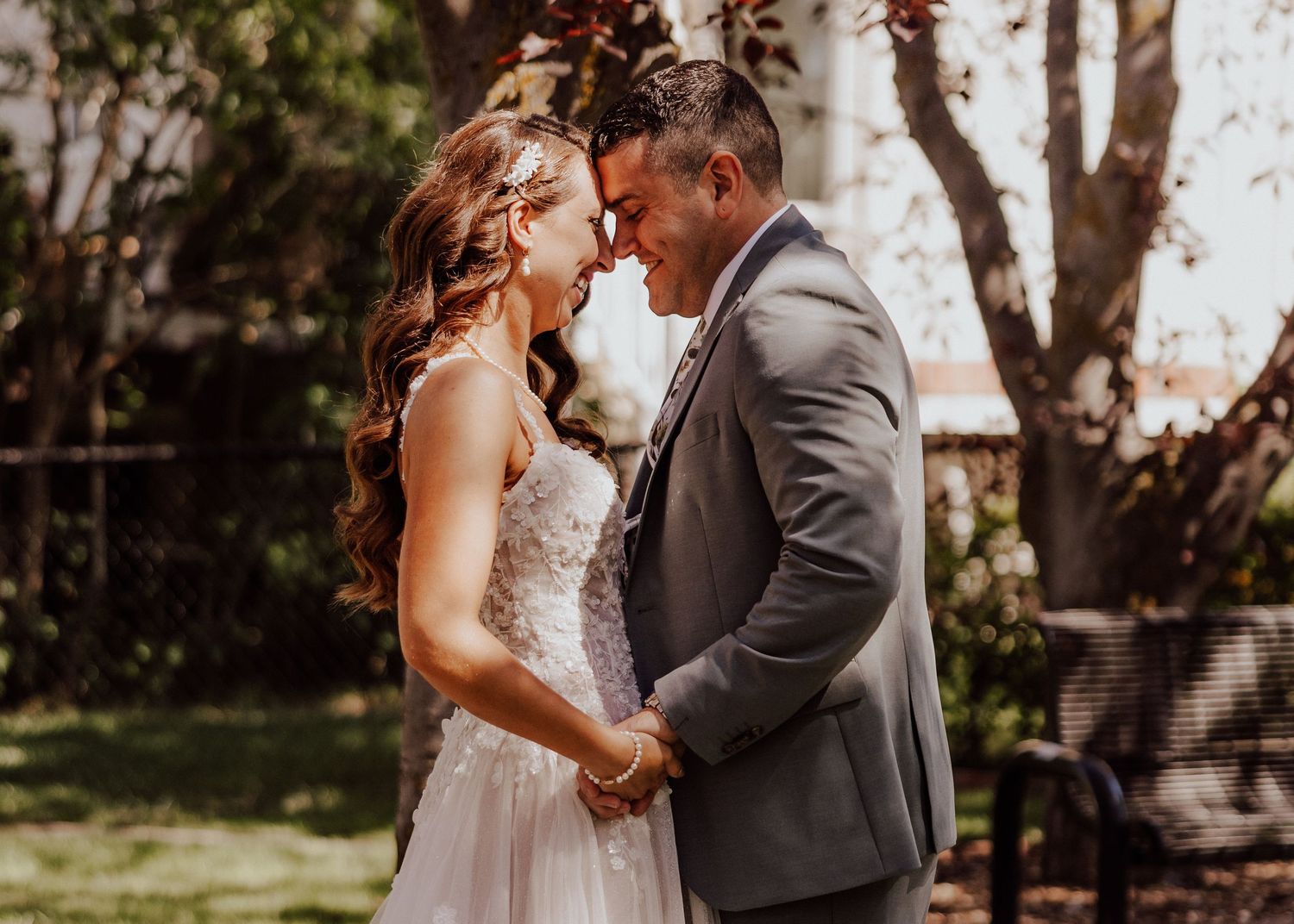 A romantic wedding couple shares an intimate moment in a garden setting during golden hour lighting.