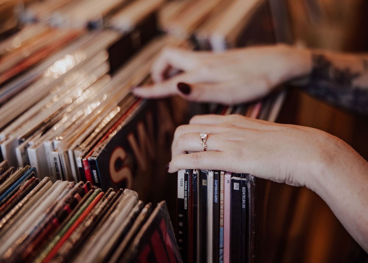 Hands with a diamond ring browsing vinyl records in a music store.