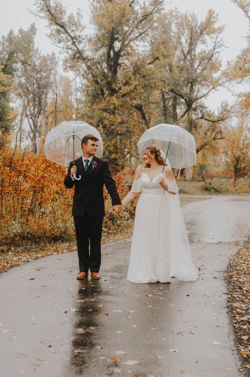 Calgary, Alberta wedding bride and groom in rain with clear umbrellas