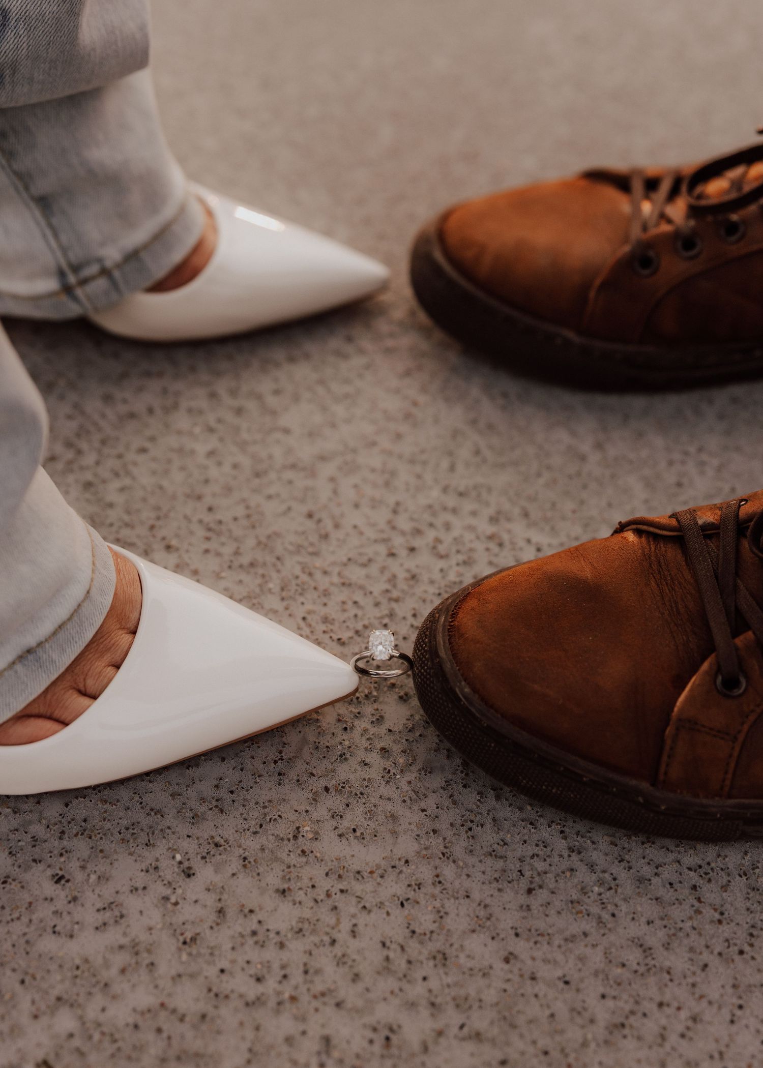 Contrasting footwear with white heels and brown boots on concrete surface.