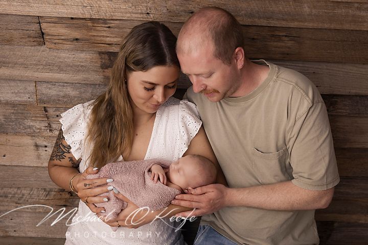 A family shares tender moments together in a rustic setting with wooden wall backdrop.
