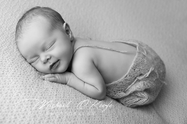 Peaceful newborn baby sleeping on soft textured blanket in black and white photography.