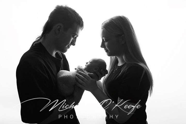 Black and white silhouette photo of new parents cradling their newborn baby, by Michael O'Keefe Photography.