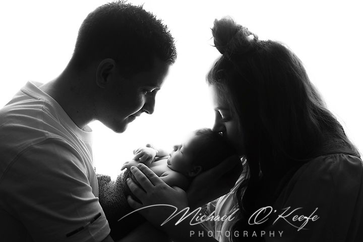 Tender family moment captured in dramatic black and white silhouette.