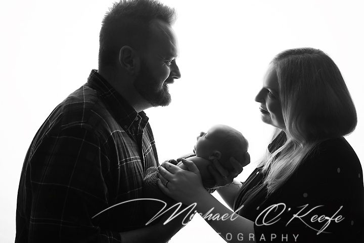 Black and white silhouette photo of parents tenderly holding their newborn baby by Michael O'Keefe Photography.