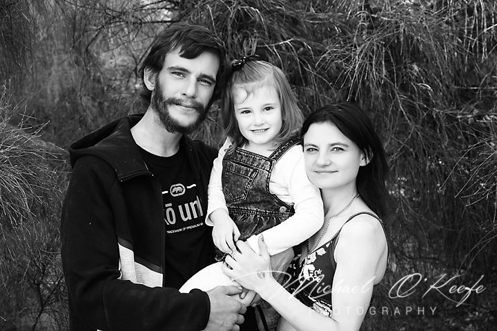 A series of black and white family portraits showing tender moments between adults and children in outdoor settings.