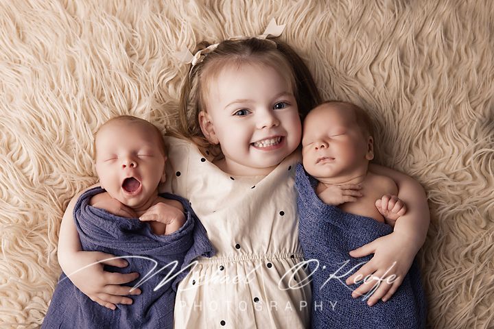A series of black and white newborn photography portraits on textured cream colored backgrounds.