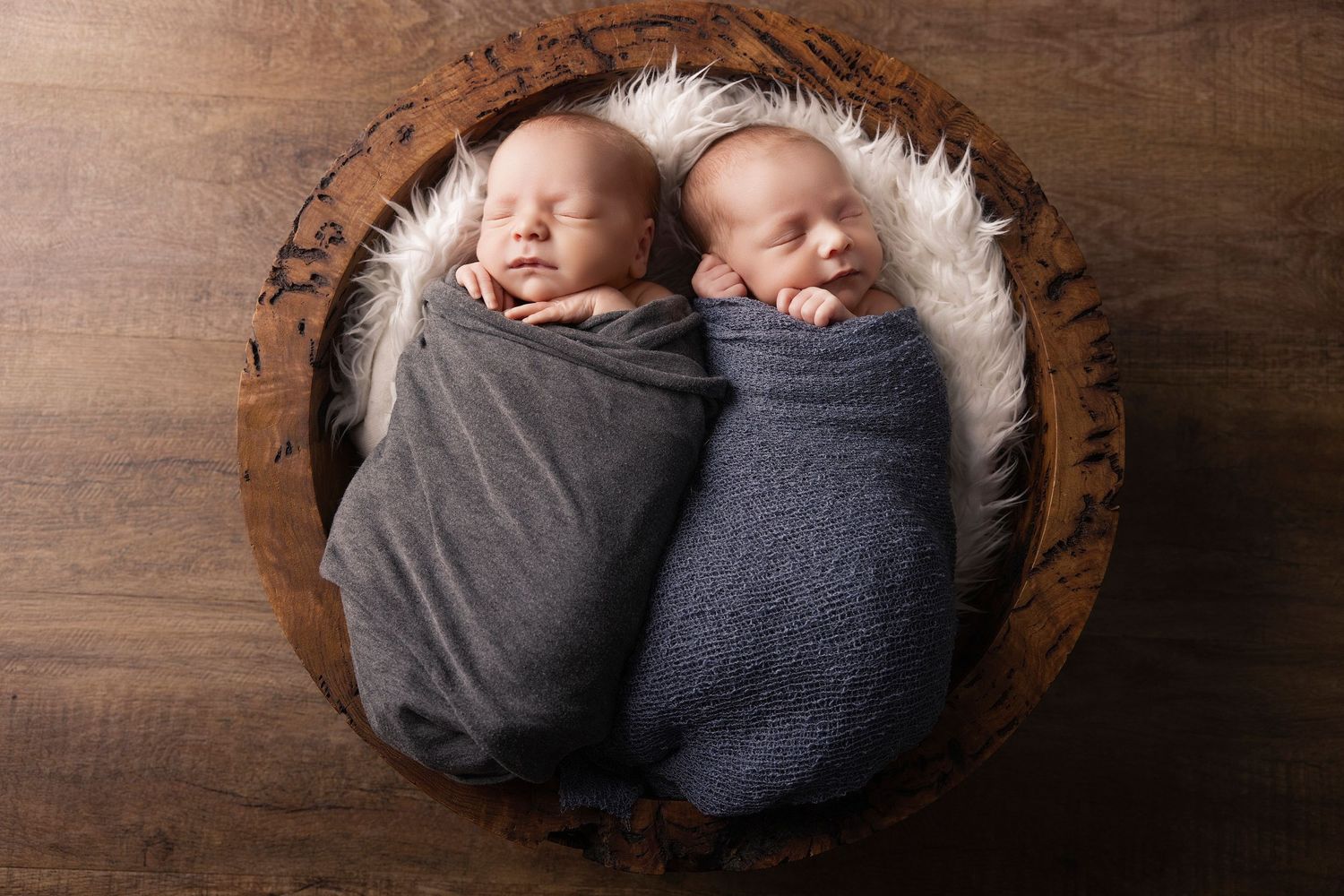 Baby sleeping peacefully on wooden floor with soft sweaters cushioning their small curled up form.