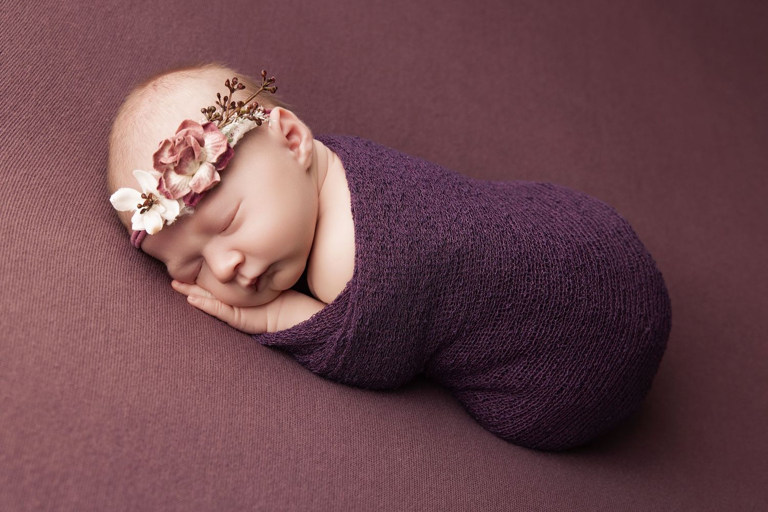 Collection of professional newborn photography poses on purple backdrop showing wrapped infant in various sleeping positions.