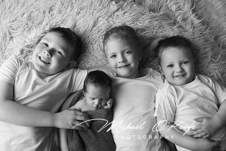 Black and white photo series showing babies lying together on a fluffy white rug.