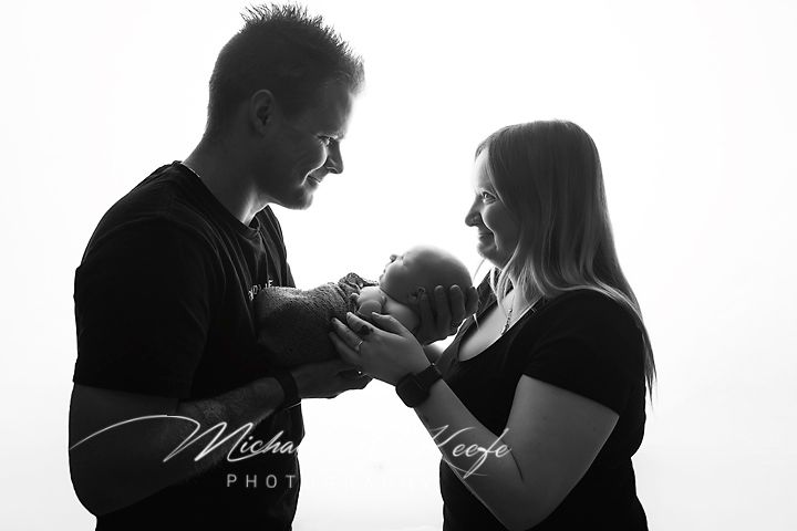 Black and white newborn photo of parents cradling their baby, captured by Michael Hoefe Photography.