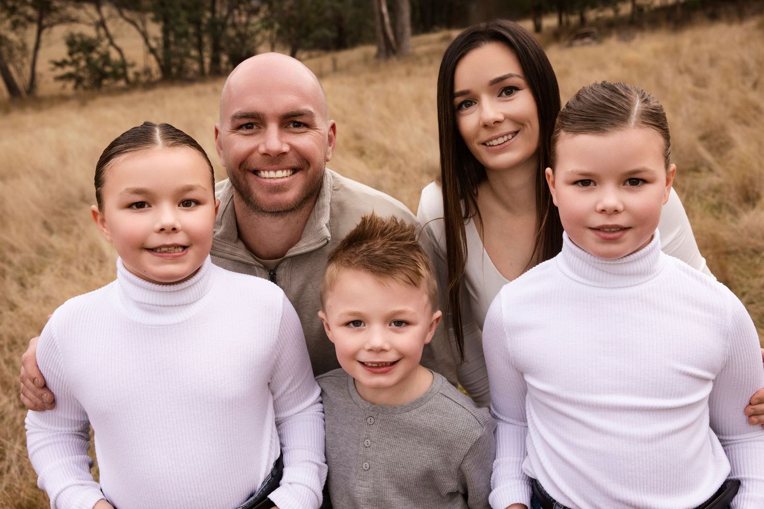 Family portrait outdoors with everyone wearing coordinating white and neutral clothing.