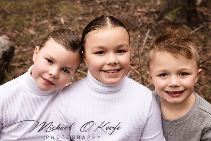 Close up portrait of children smiling together against blurred natural background.