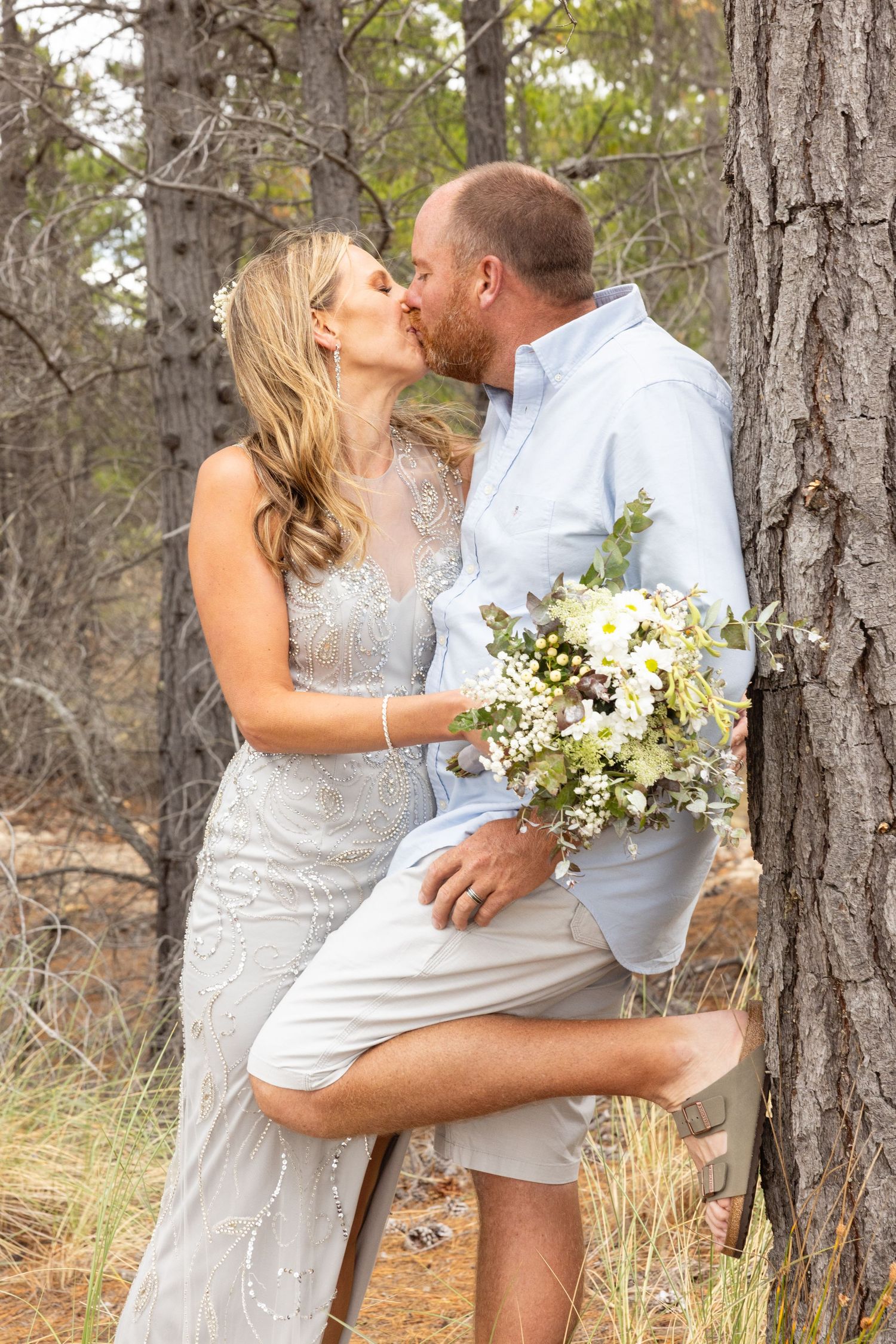 Wedding photos captured among tall pine trees showing intimate moments between newlyweds with white bouquet.