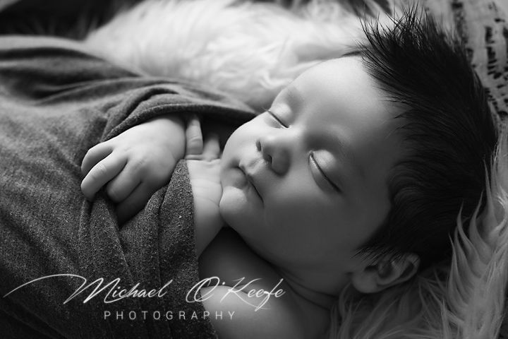 A series of black and white artistic photographs showing a sleeping baby in various peaceful poses.