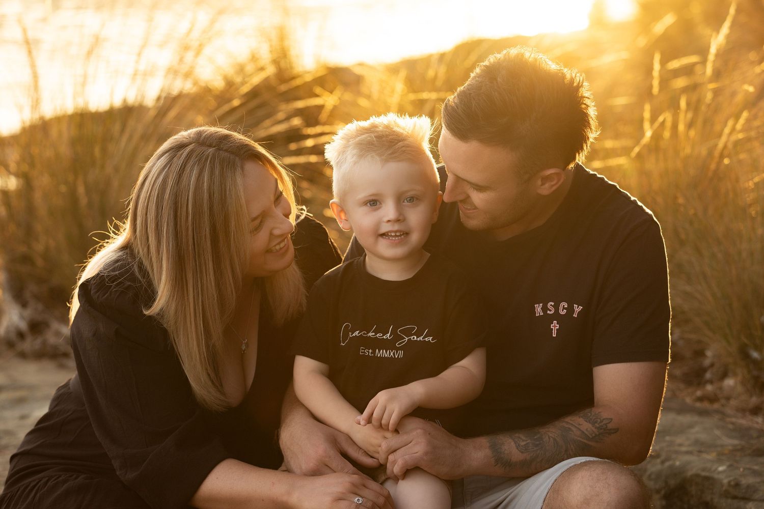 Family portrait at sunset with warm golden light filtering through natural scenery.