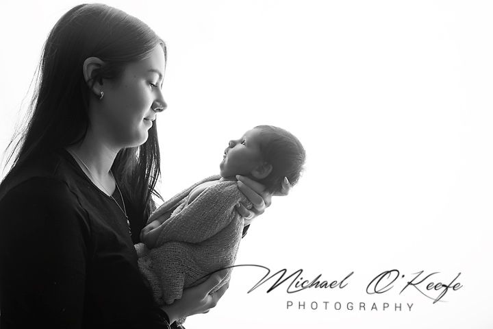 Black and white photo of a mother tenderly holding her newborn baby, captured by Michael O'Keeffe Photography.