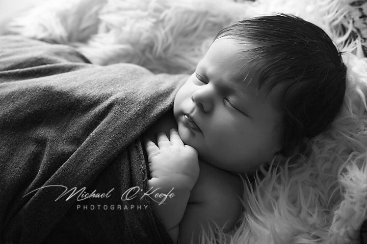 A black and white photo series showing a sleeping infant in soft, dreamy lighting against textured blankets and fabrics.