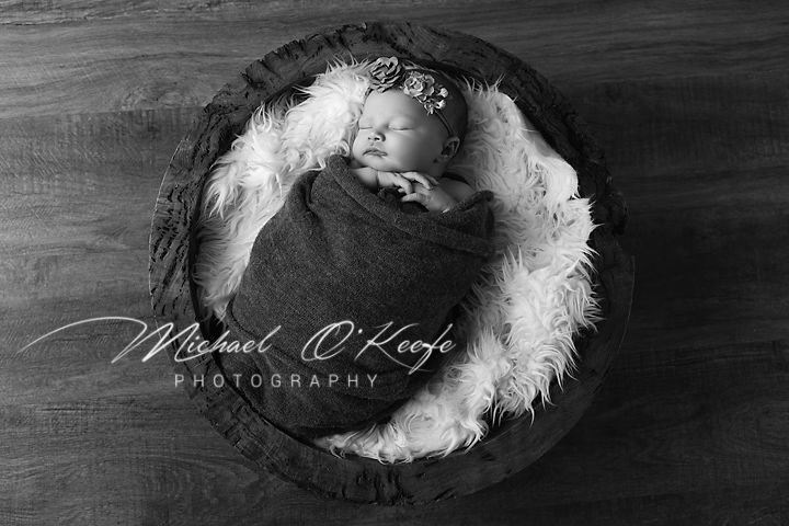 A delicate white feather lies on a dark wooden surface, creating a striking contrast in black and white photography.