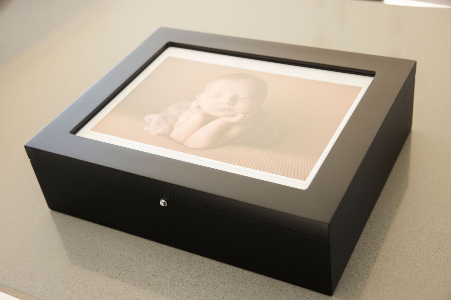 Black wooden keepsake box with glass window display on grey surface.