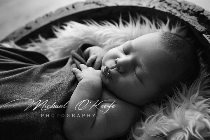 Black and white portrait of sleeping baby on soft furry surface.