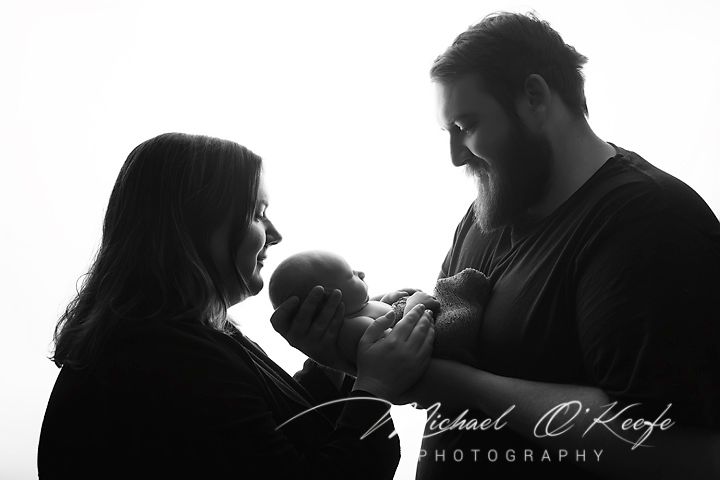 Black and white newborn photo of parents tenderly holding their baby, captured by Michael O'Keefe Photography.