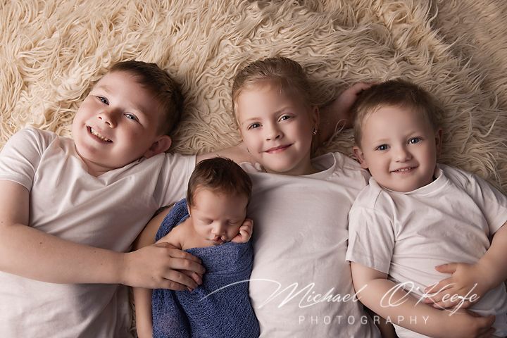 A series of six connected photos showing siblings lying together on a beige fluffy rug in matching outfits.