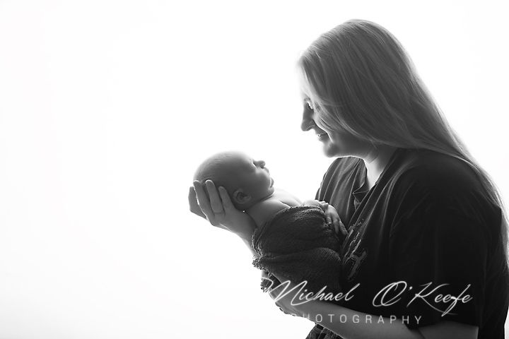 Black and white photo of a mother tenderly holding her newborn baby, captured by Michael O'Keefe Photography.