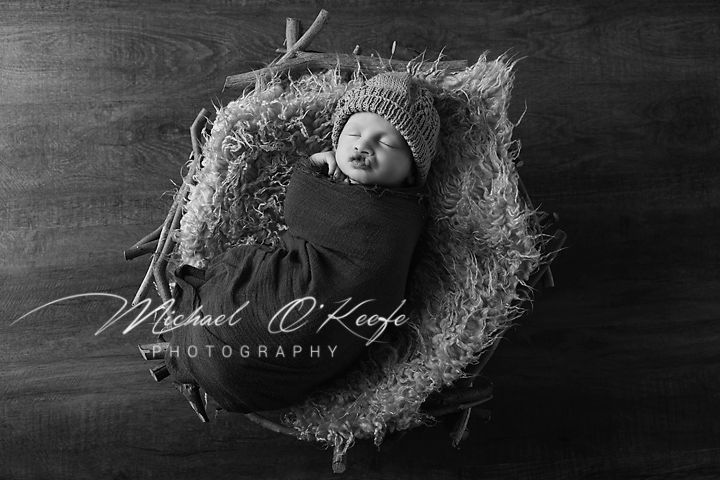 Black and white artistic portrait with curly hair against dark textured background and photography signature.